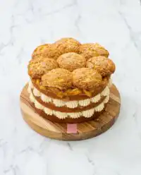 A tall Peach Cobbler Layer Cake with three layers and a decorative biscuit topping.