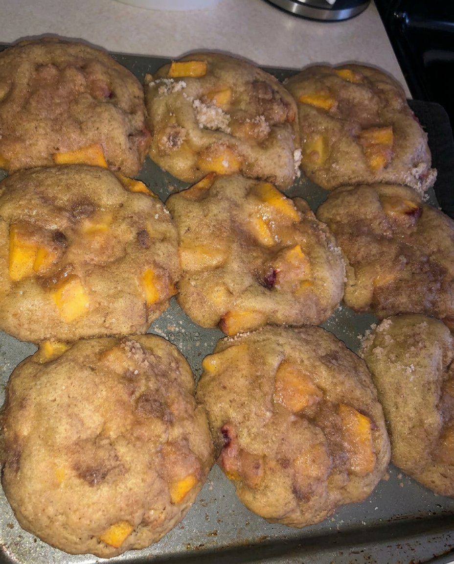 A peach cobbler muffin on a white plate next to a cup of coffee.