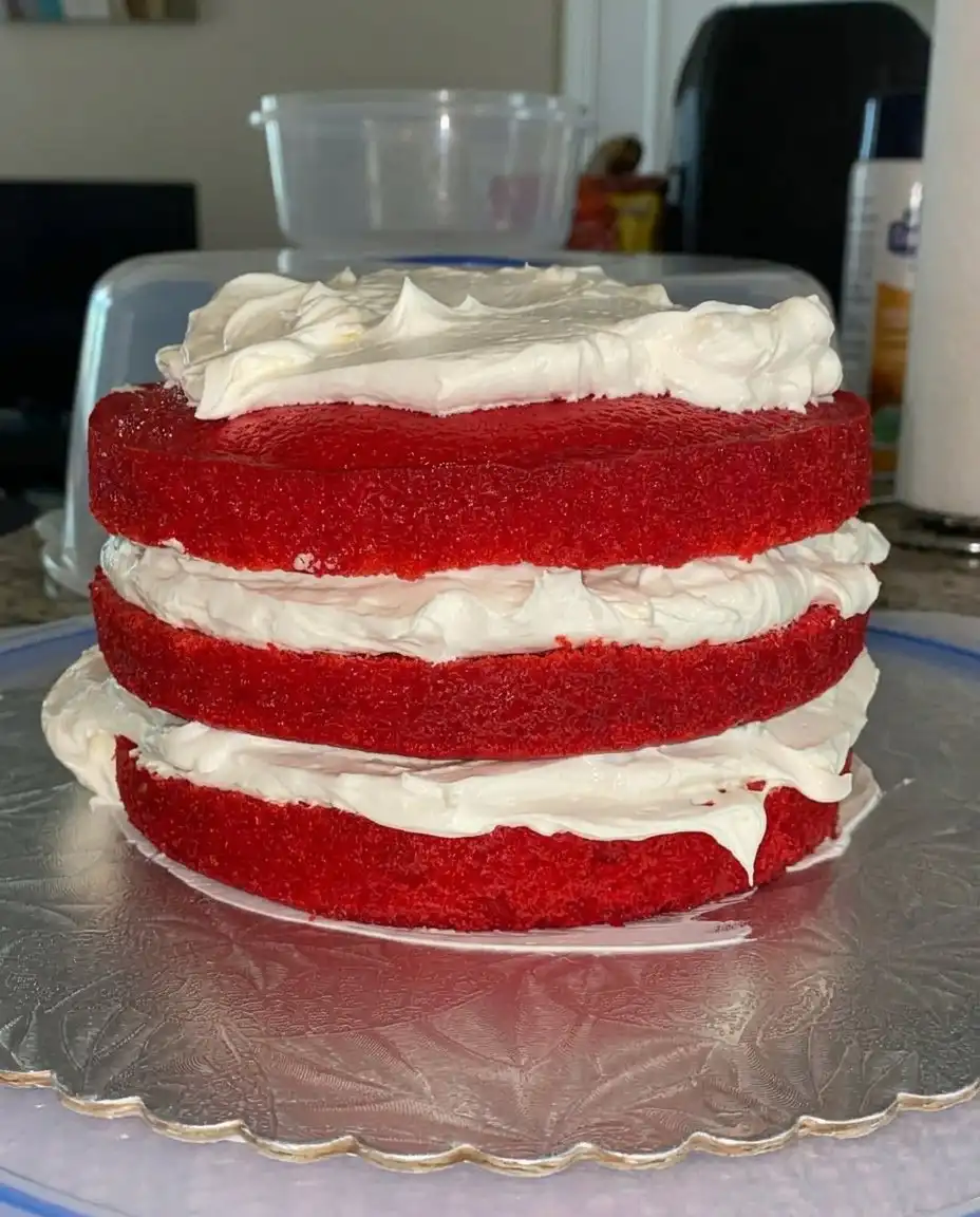 Pouring red strawberry gelatin over a poked white cake.
