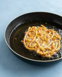 A golden brown Pumpkin Spice Funnel Cake dusted with powdered sugar on a white plate.