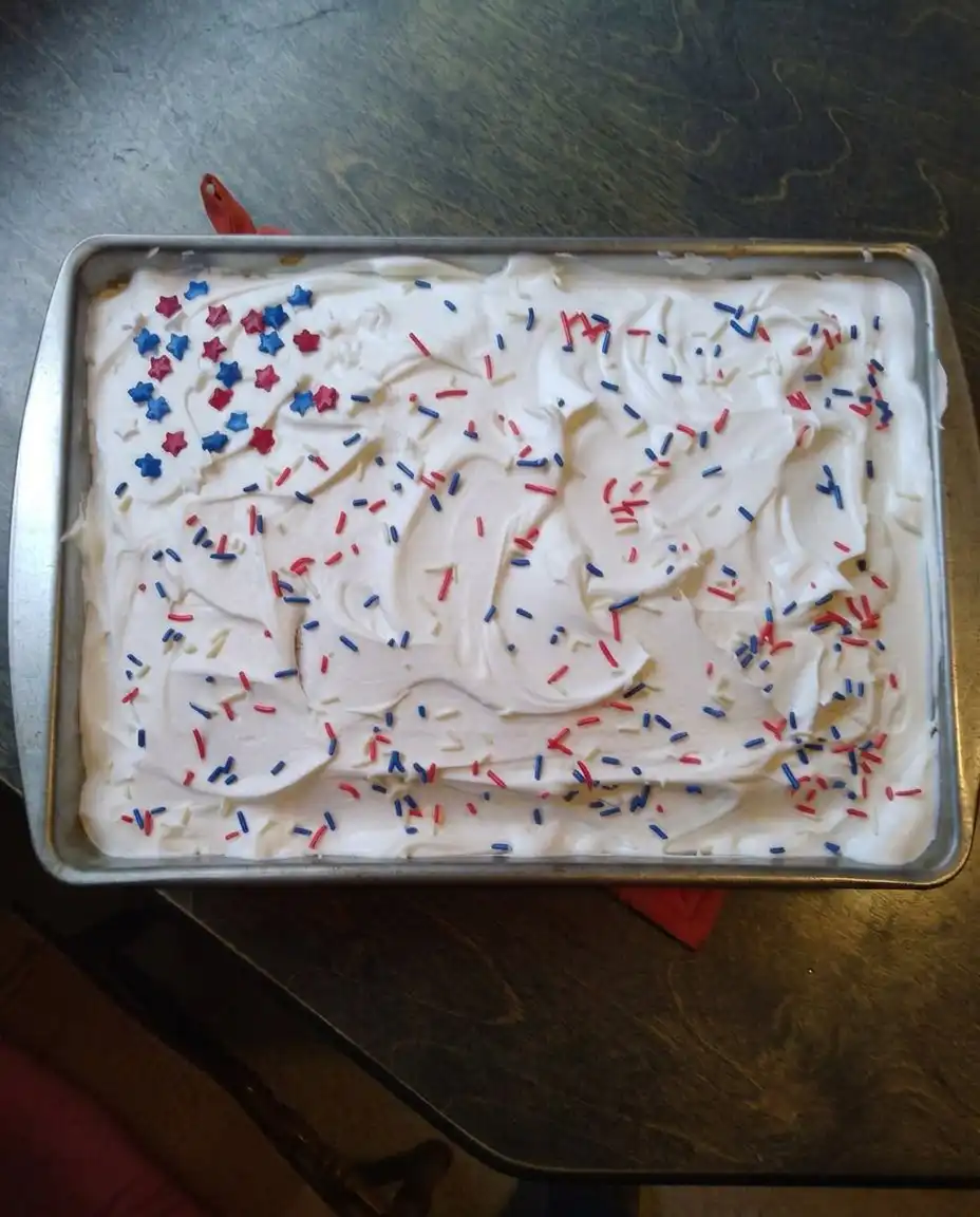 A single slice of poke cake showing red and blue vertical stripes inside