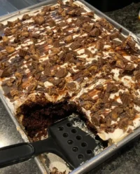A 9x13 chocolate poke cake topped with peanut butter frosting and chopped peanut butter cups
