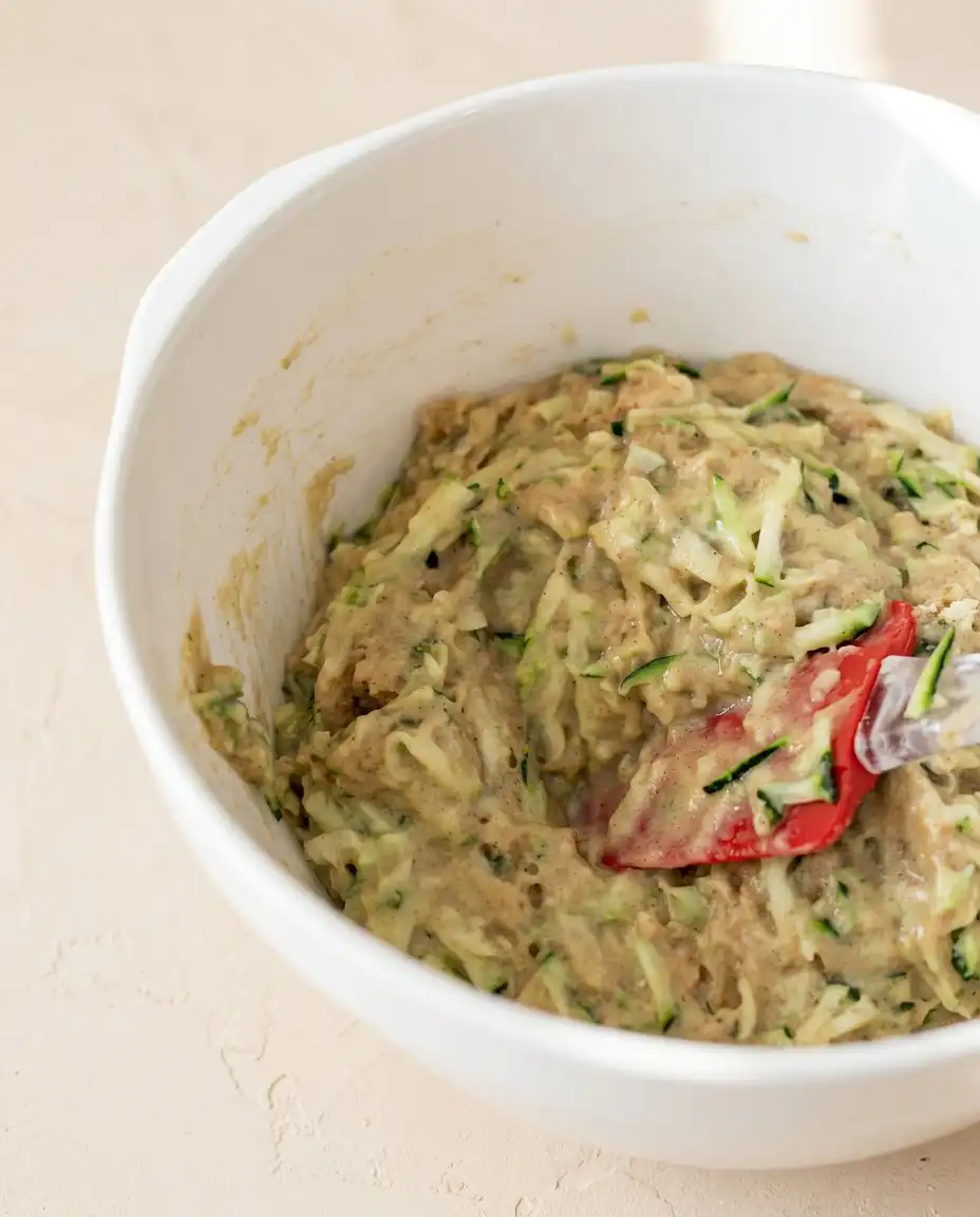 Chocolate Chip Zucchini Muffins 15 Wooden spoon scooping Chocolate Chip Zucchini Muffins batter into a lined tin.