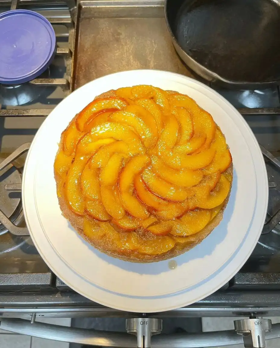 A slice of peach cake topped with a scoop of vanilla ice cream