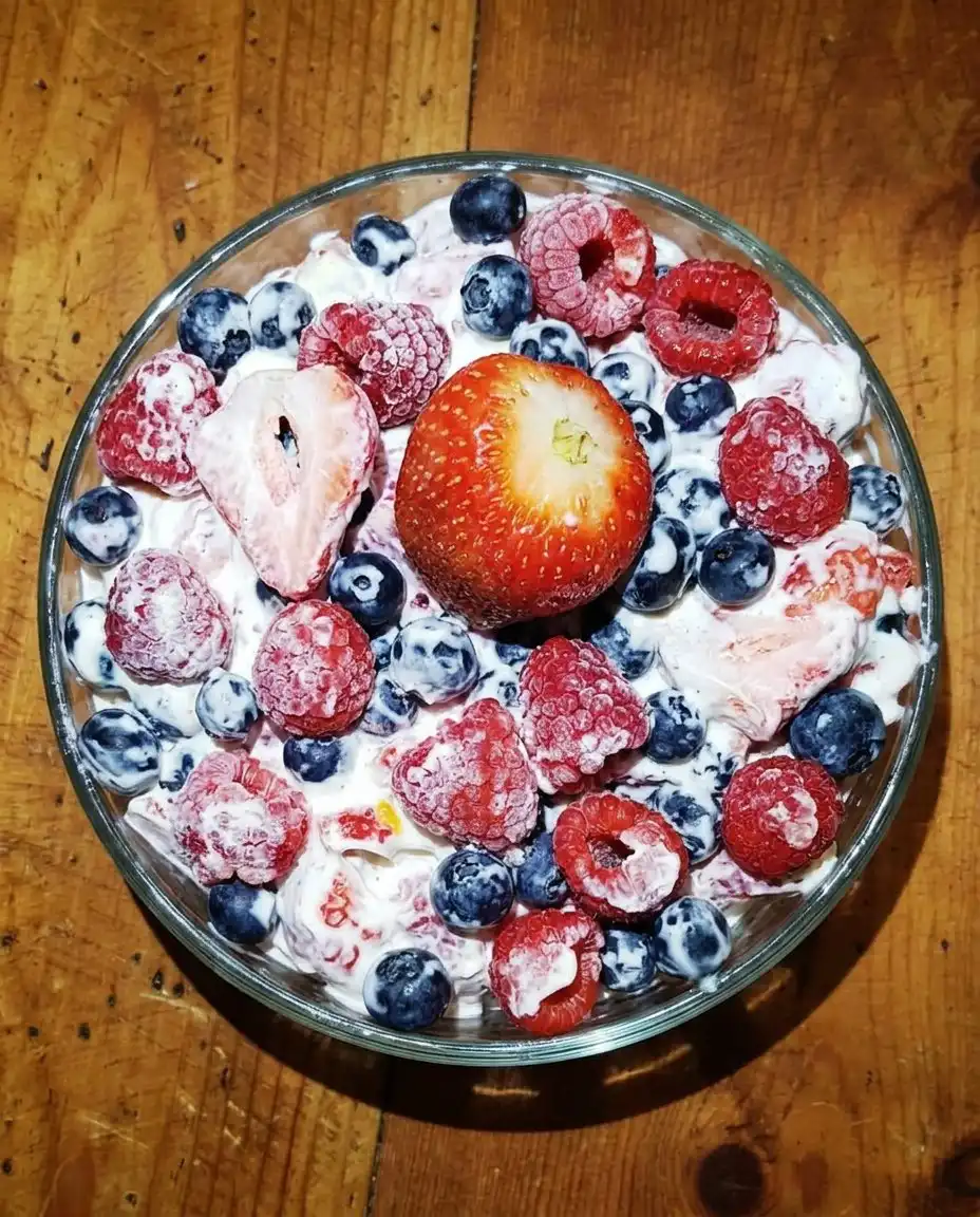 Individual servings of cheesecake salad on a wooden picnic table with a blue napkin.