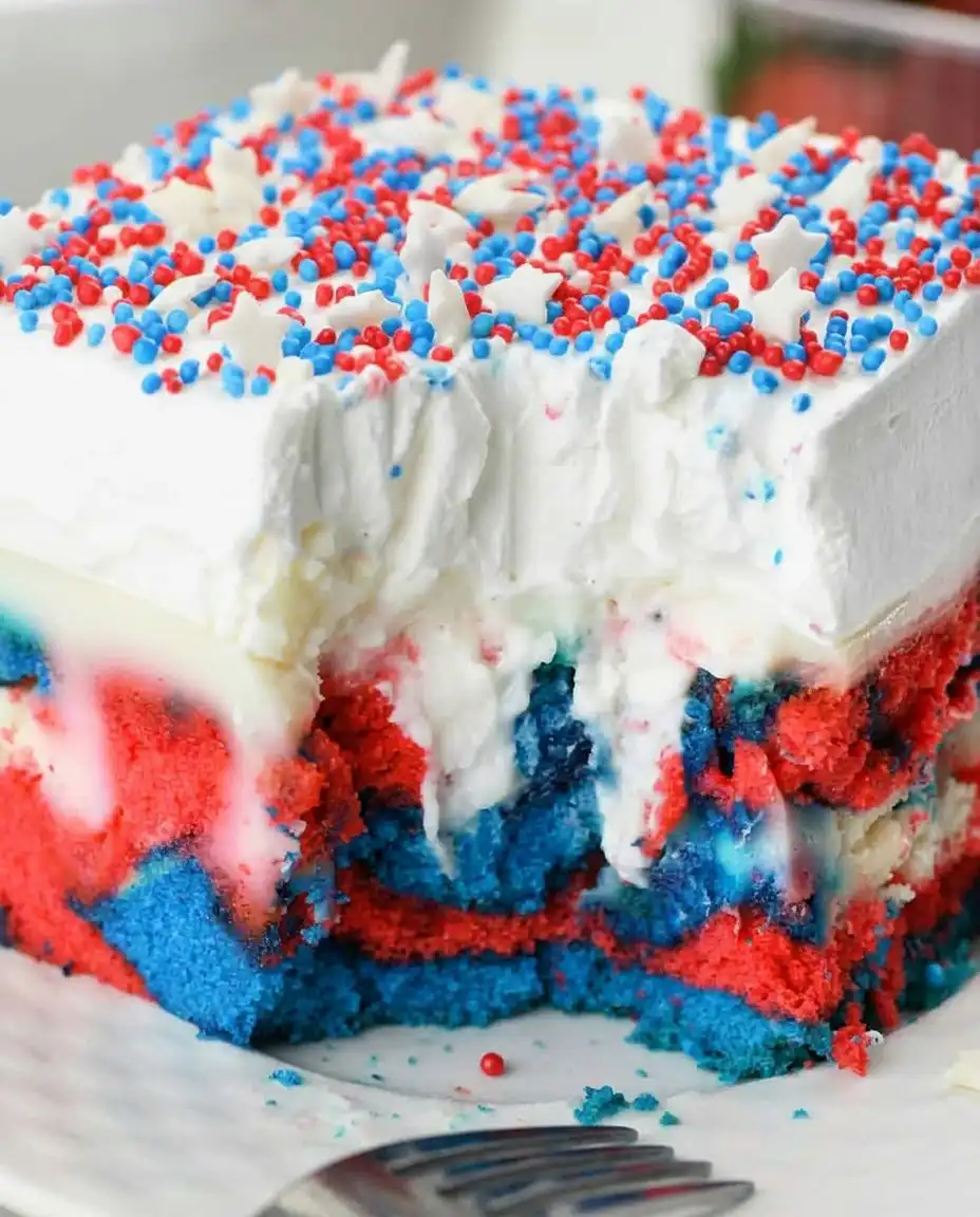 A spatula lifting a square of patriotic poke cake from a glass 9x13 dish
