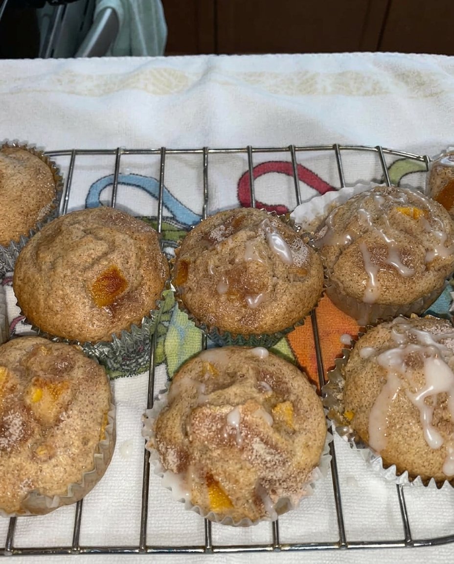 A peach cobbler muffin on a plate next to a cup of coffee