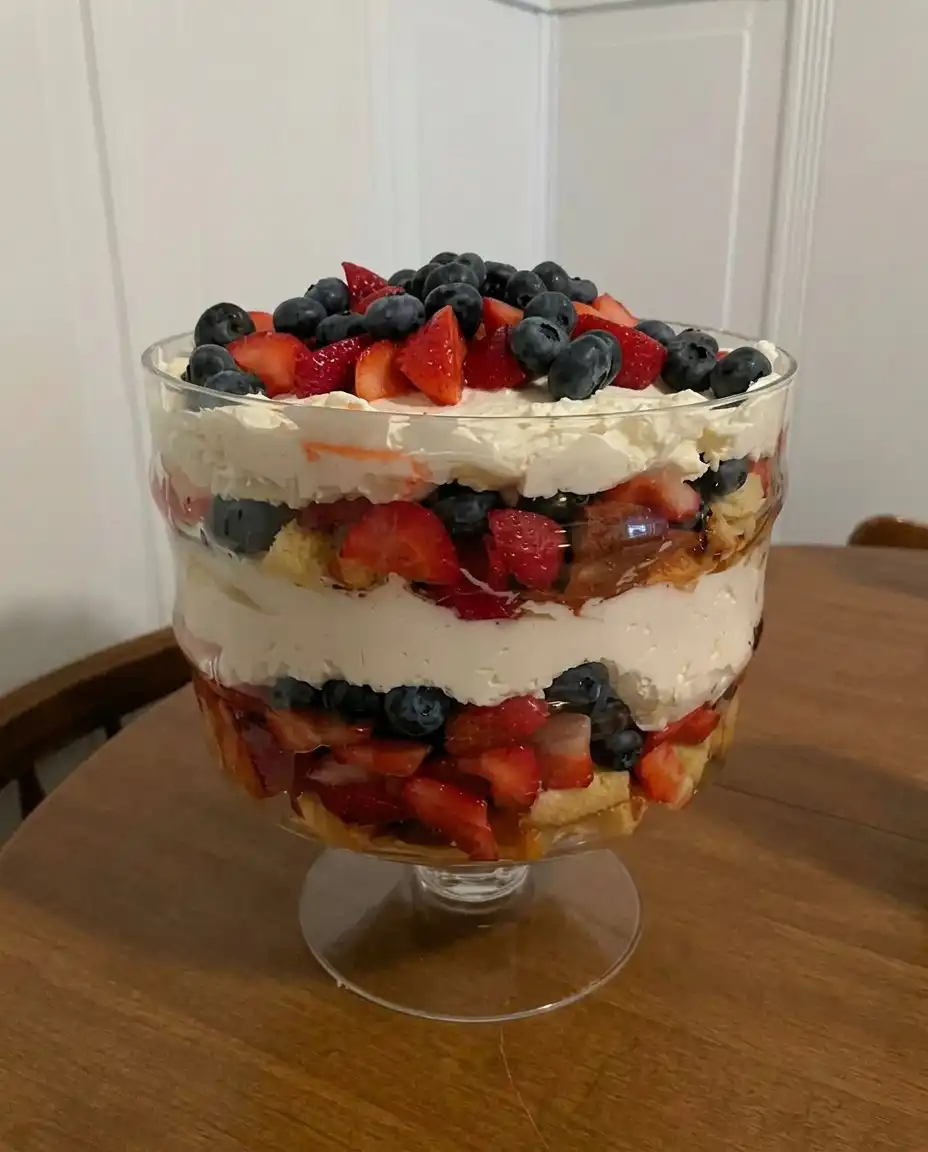 A large scoop of patriotic trifle being served onto a white plate showing all the distinct colorful layers