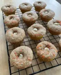 A stack of fresh carrot cake zucchini muffins on a kitchen counter