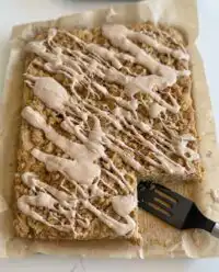 A freshly baked zucchini crumb cake with cinnamon glaze on a wooden counter