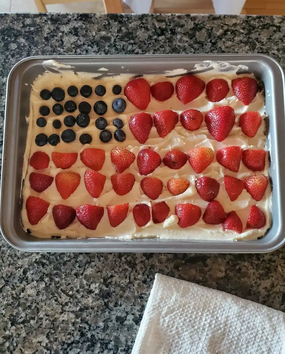 A single slice of flag cheesecake on a white plate with a fork.
