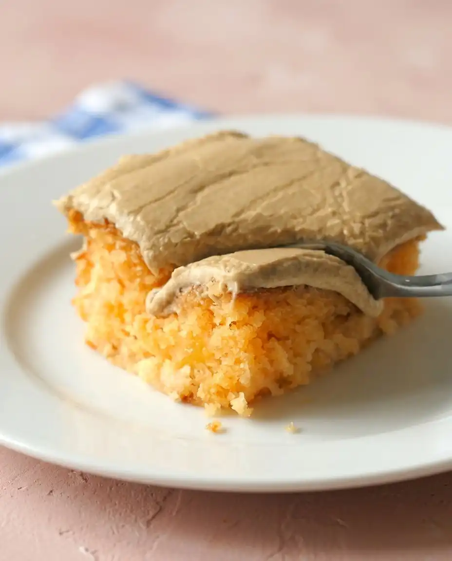 A slice of peach cake with brown sugar frosting next to a steaming cup of coffee.