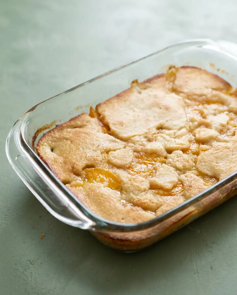 A single serving of Peach Cobbler with Canned Peaches topped with melting vanilla ice cream.