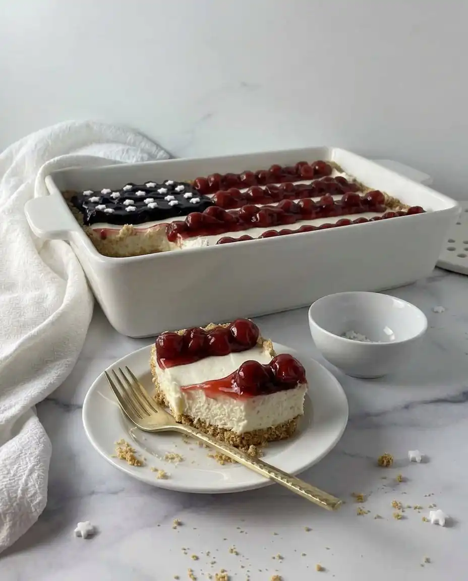 A generous square of no-bake cheesecake decorated like an American flag served on a casual plate.