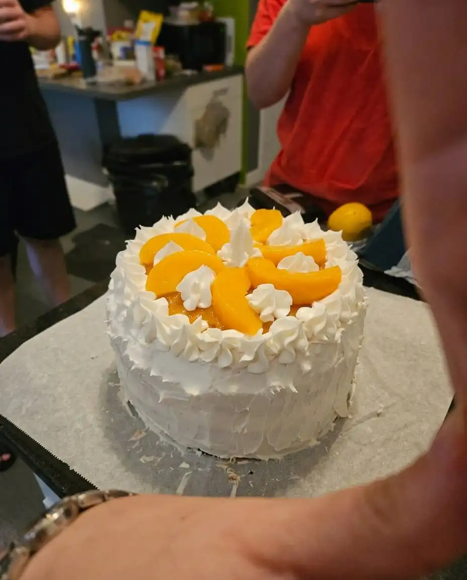 A slice of peaches and cream layer cake on a white plate with a fork