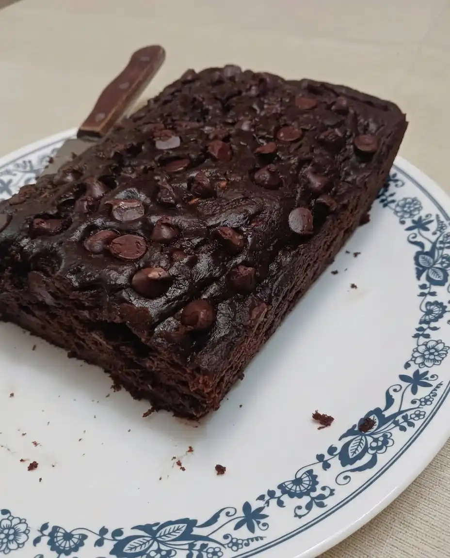 A knife slicing through a moist loaf of chocolate zucchini bread