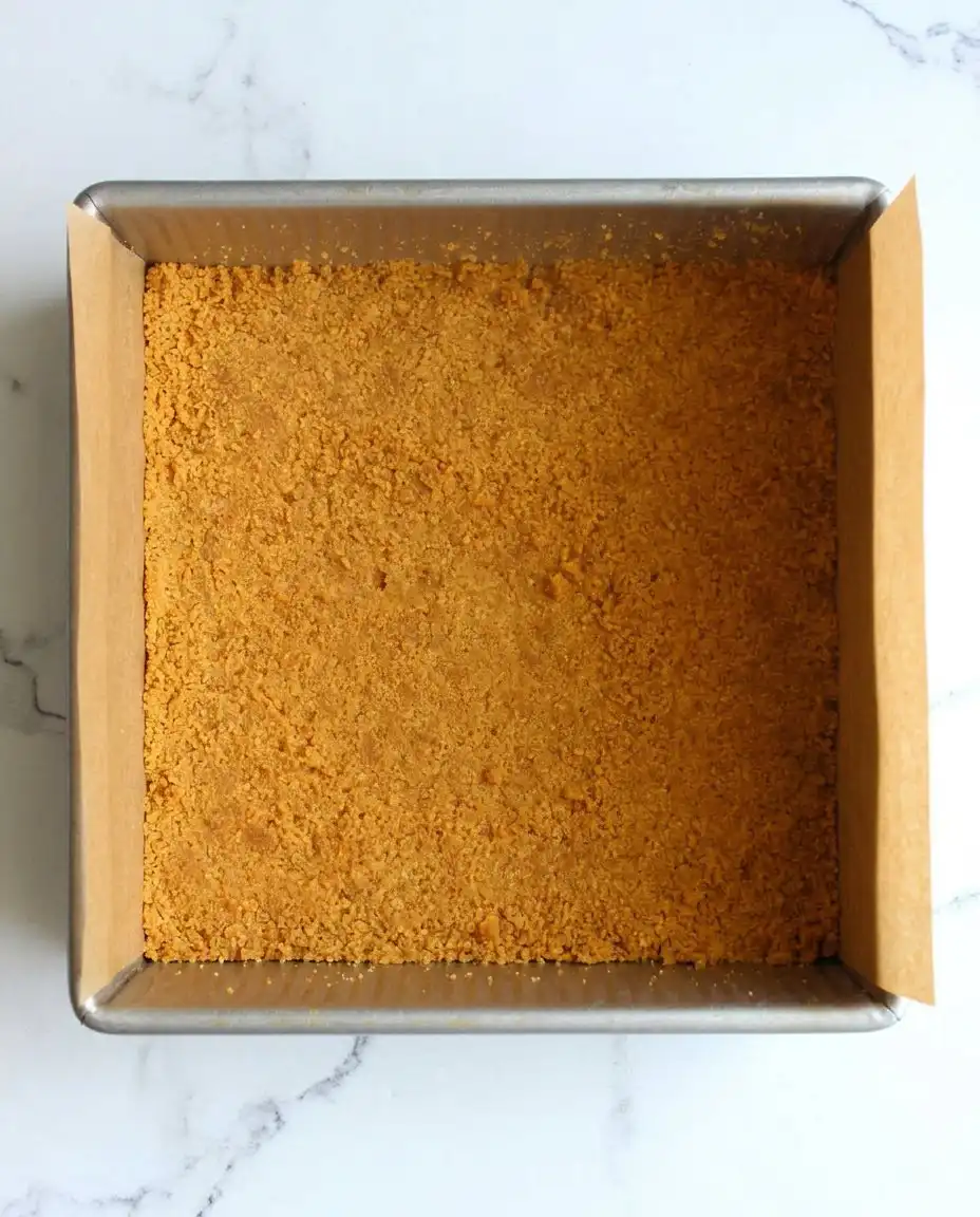 A person slicing chilled cheesecake bars into clean squares