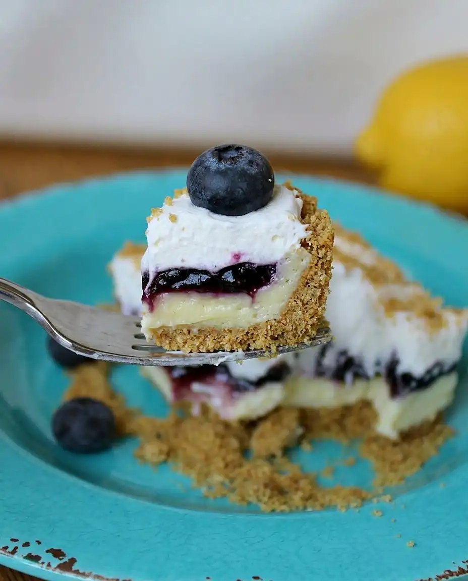 A spatula spreading thick lemon filling over a graham cracker crust