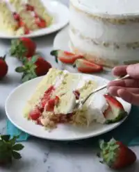 A three layer strawberry shortcake cake with whipped cream and fresh berries