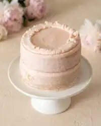 A beautiful white and pink Two-Layer Smash Cake sitting on a wooden table ready for a party.
