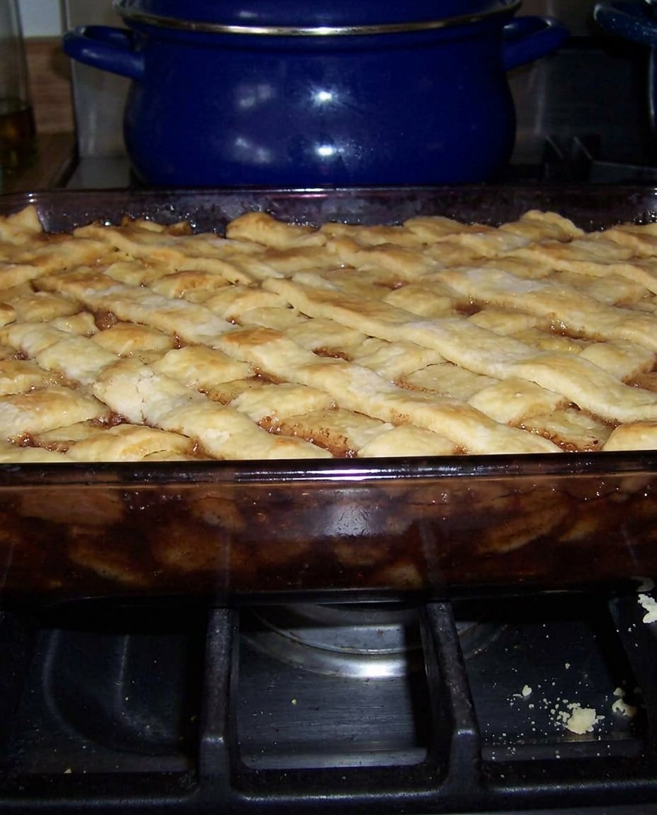 A bowl of peach cobbler topped with melting vanilla ice cream.