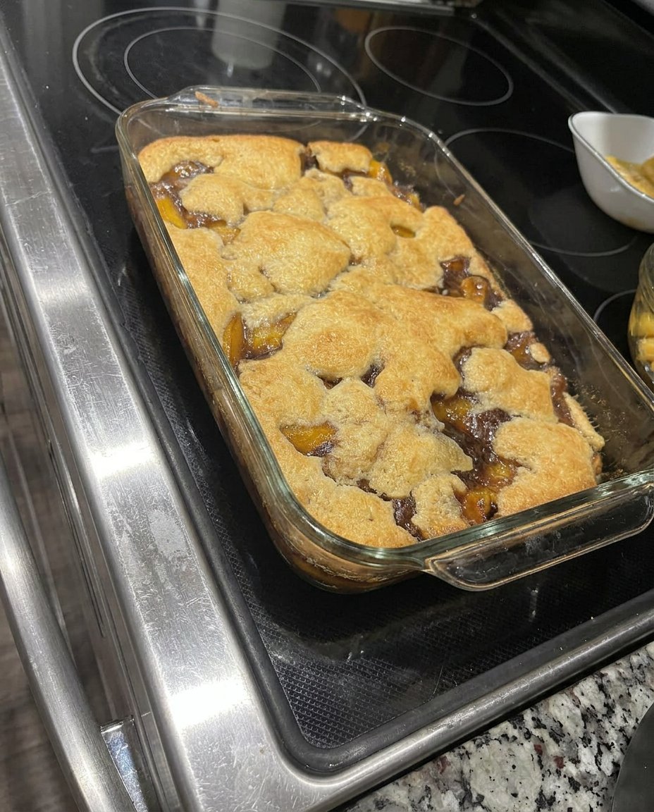 A bowl of warm peach cobbler topped with a melting scoop of vanilla ice cream.