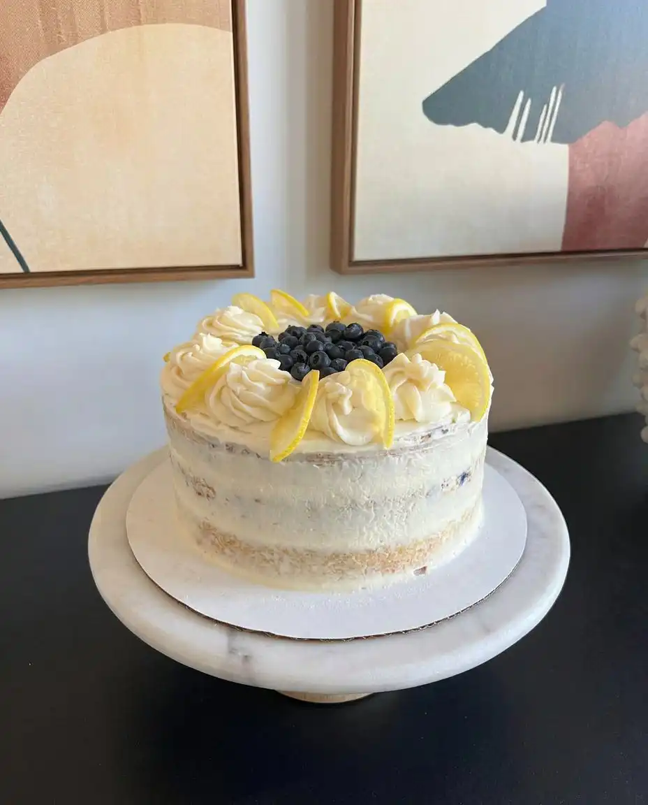 A whole lemon blueberry cake topped with fresh berries