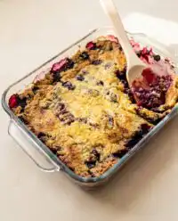 A warm, golden-brown 3-ingredient blueberry dump cake in a glass baking dish.
