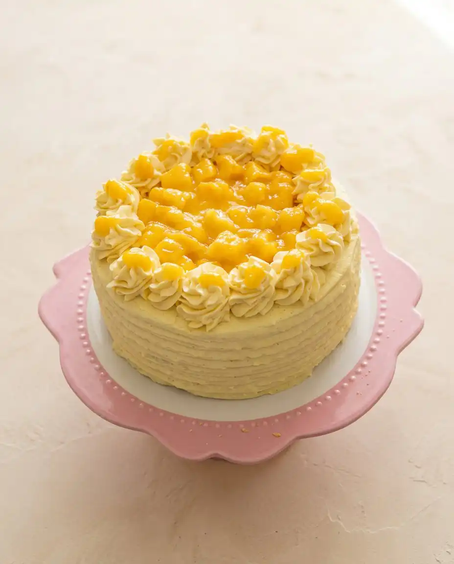 A neat slice of Mango Ombre Cake showing the light orange cream layers next to a cup of coffee.