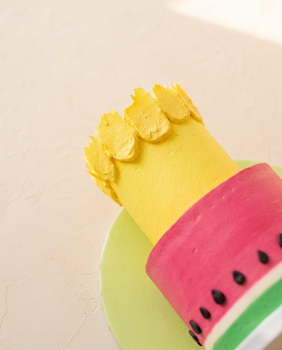 Assembling a beautiful Watermelon and Pineapple Tropical Fruit Cake using wooden toothpicks to secure the tiers.