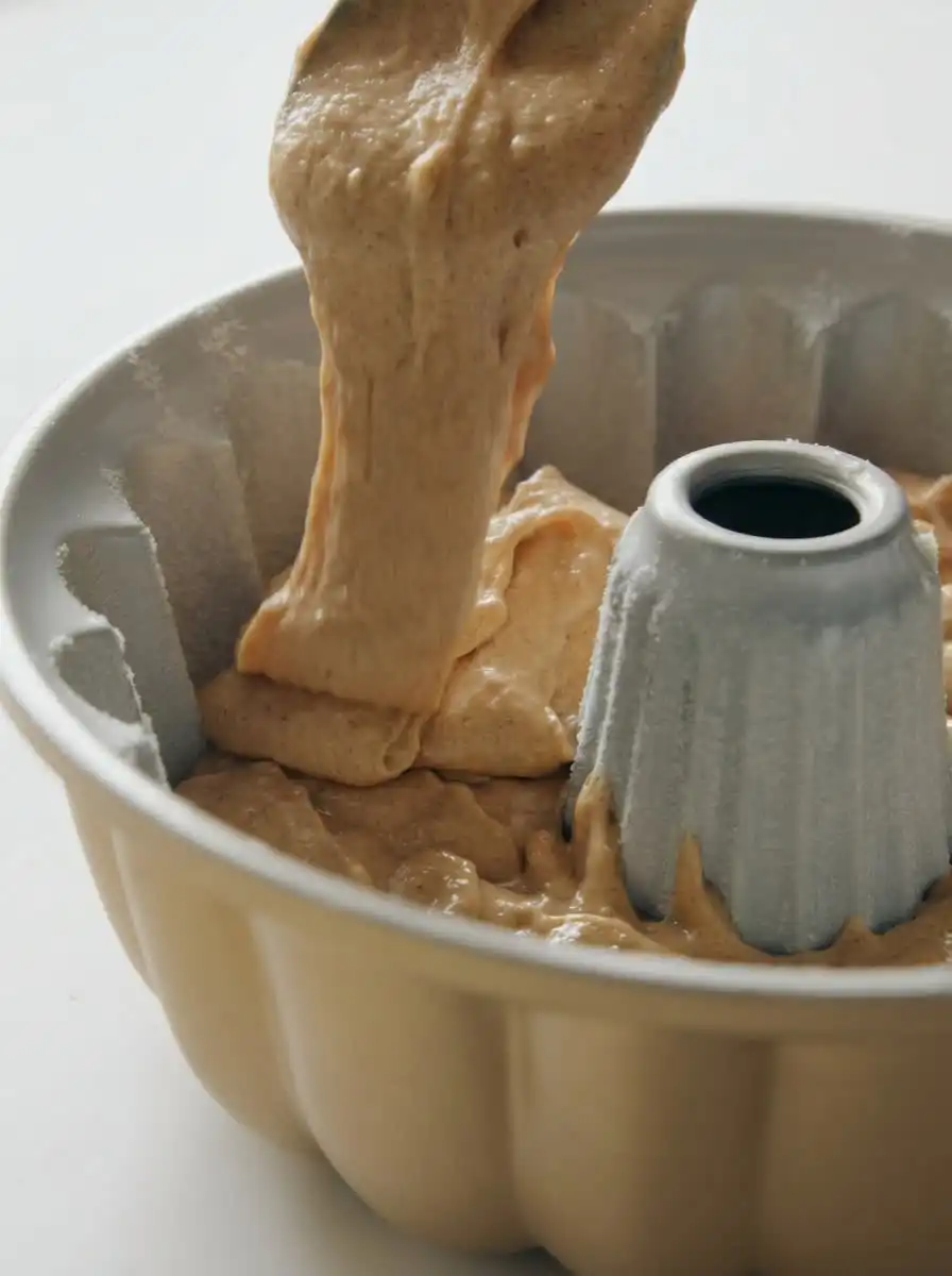 A pastry brush coating a warm apple cider cake with melted butter and cider mixture