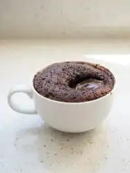 A warm Chocolate Lava Mug Cake in a rustic ceramic mug on a wooden kitchen counter.