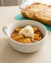 A warm Cinnamon Canned Peach Dump Cake fresh out of the oven sitting on a rustic kitchen counter.