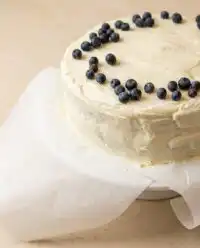 A perfect slice of Classic Blueberry Layer Cake on a beautiful glass dessert stand.