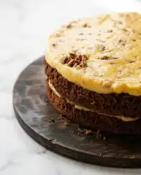 A rustic homemade German Chocolate Cake sliced on a wooden stand in a cozy home kitchen.
