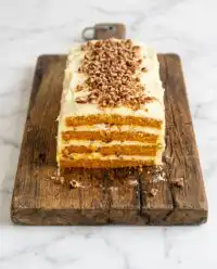 A grand Classic Pumpkin Layer Cake frosted with cream cheese and topped with golden pecan toffee crumble.