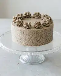 A beautiful sliced cookies and cream birthday cake decorated with whipped buttercream frosting on a white stand.