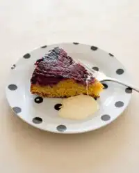 A fresh blackberry upside down cake sitting on a wire cooling rack after being flipped.