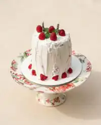 A whole Watermelon Cake with Whipped Coconut Frosting topped with fresh berries on a rustic wooden table.