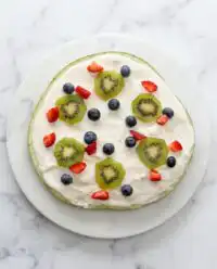 A beautiful cold Watermelon Pizza Cake topped with white cream and fresh summer berries