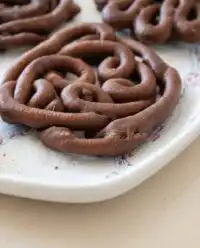 A golden-brown crispy Chocolate Funnel Cake dusted generously with powdered sugar on a plate
