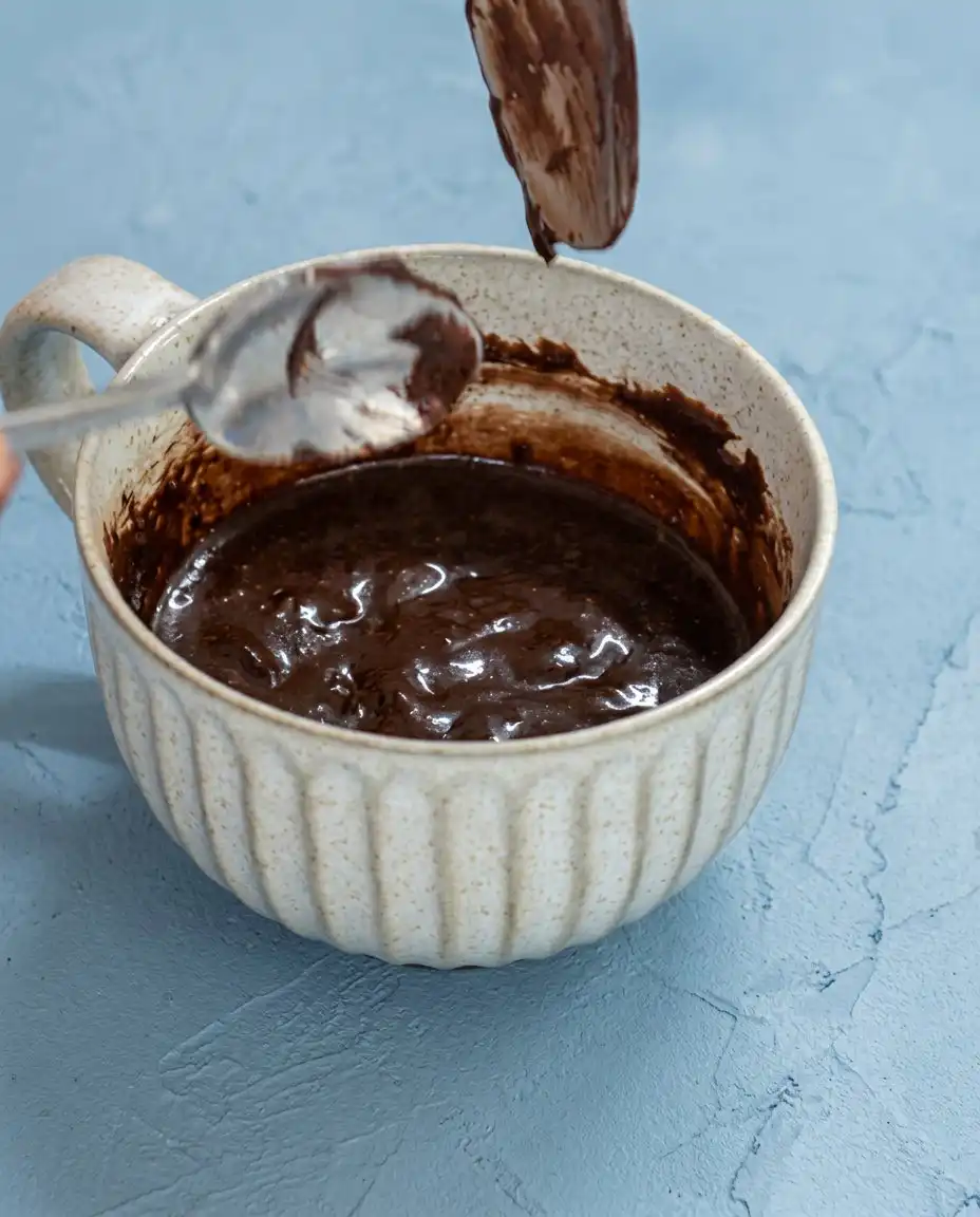 Measured dry and wet ingredients for making a quick chocolate mug cake displayed on a counter.