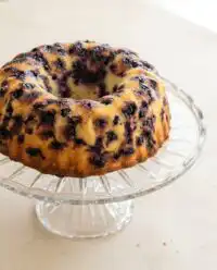 A gorgeous Lemon Blueberry Bundt Cake with Lemon Glaze on a white serving platter