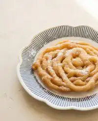 Crispy pancake mix funnel cake frying to a perfect golden brown in a hot skillet on the stove.