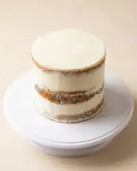 A gorgeous three layer vanilla naked cake decorated with fresh red raspberries on a white stand