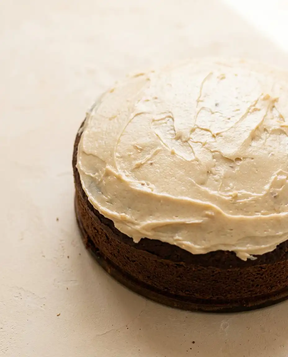 Serving a thick slice of Marzipan Carrot Topped Cake on a beautiful china plate next to tea.