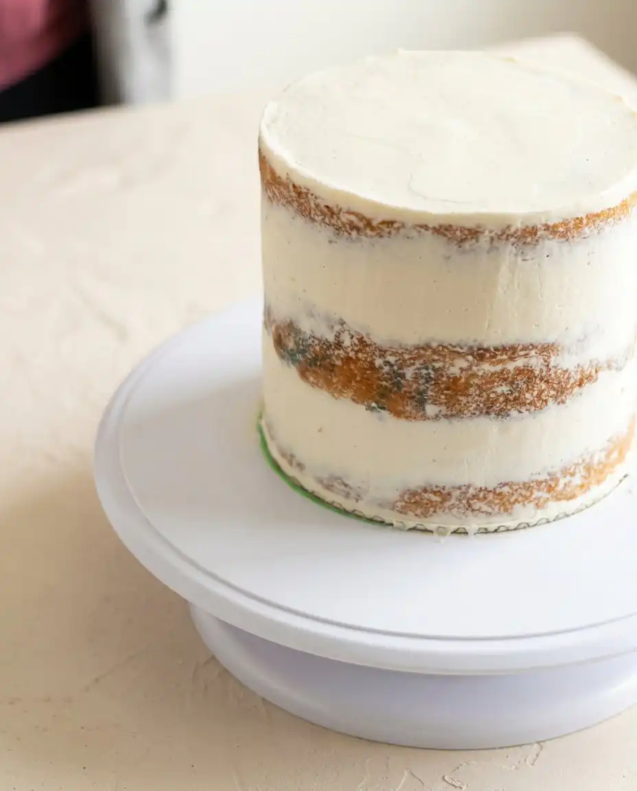 A sharp knife slicing a neat portion of a three layer vanilla naked cake with raspberries
