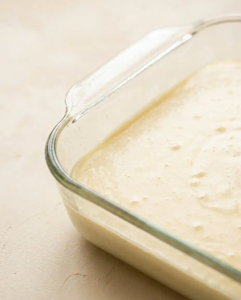 Slicing a freshly baked Pineapple Sheet Cake with Cream Cheese Frosting with a clean knife.