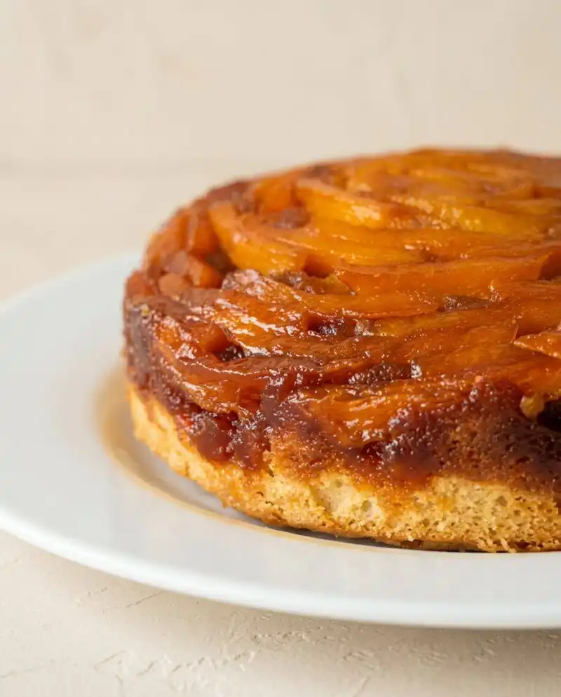 A golden Mango Upside Down Cake resting on a rustic wooden counter.
