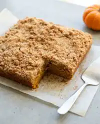 A warm slice of Pumpkin Streusel Coffee Cake on a plate with a fork next to it.